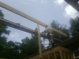 Carpenter setting a ridge beam over a new addition frame — Ice Dam Removal by Roofing Brothers in Todd